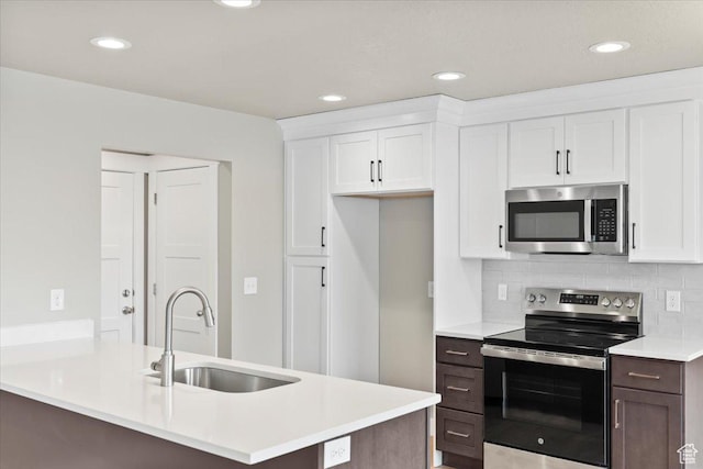 kitchen with a sink, appliances with stainless steel finishes, white cabinets, light countertops, and decorative backsplash