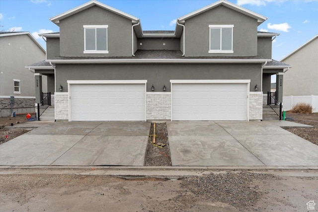 view of front of house featuring stone siding, stucco siding, concrete driveway, and a garage