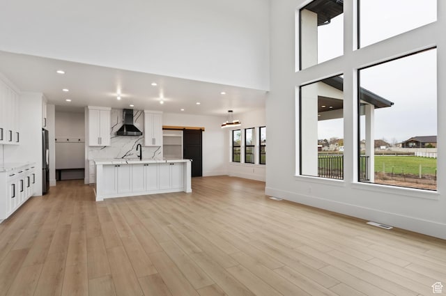 124 E 4100 N, North Ogden, UT 84414 - unfurnished living room with a high ceiling, a barn door, sink, and light wood-type flooring