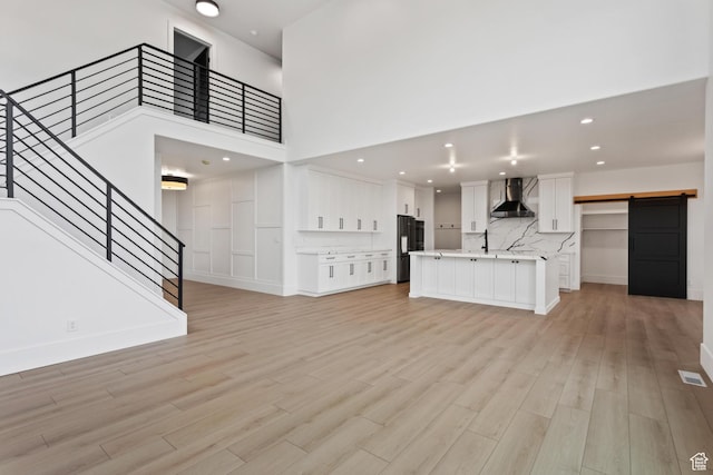 124 E 4100 N, North Ogden, UT 84414 - unfurnished living room with a barn door, a high ceiling, and light wood-type flooring