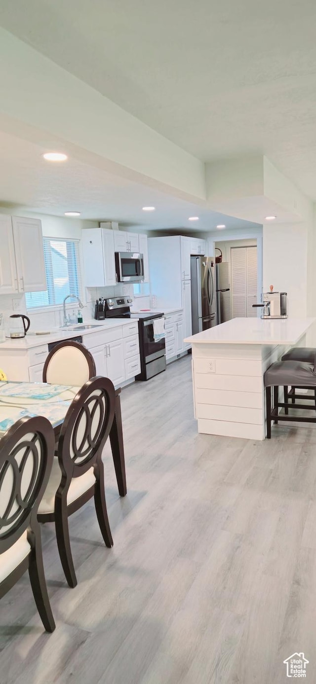 1600 W 4300 S, Salt Lake City, UT 84123 - kitchen with stainless steel appliances, a peninsula, white cabinets, recessed lighting, and light wood-type flooring