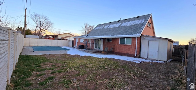 1600 W 4300 S, Salt Lake City, UT 84123 - back of property at dusk with brick siding, a patio area, a shingled roof, and a fenced backyard