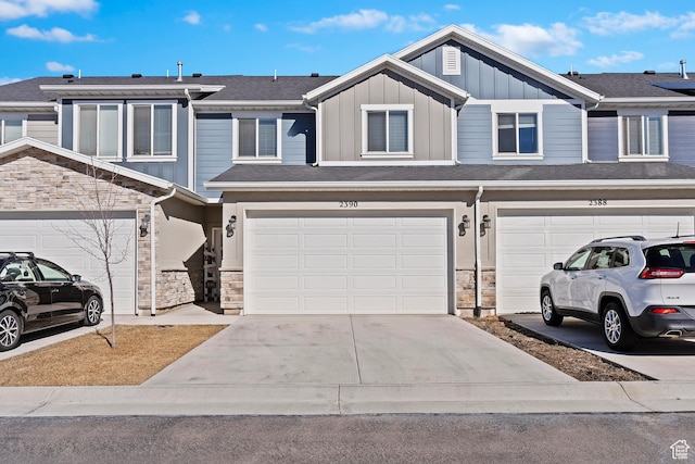 townhome / multi-family property with stone siding, board and batten siding, and driveway
