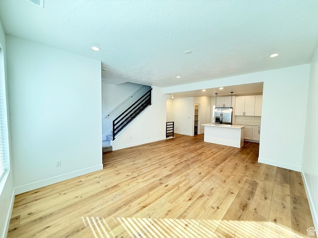 unfurnished living room featuring light wood-style floors, recessed lighting, baseboards, and stairs