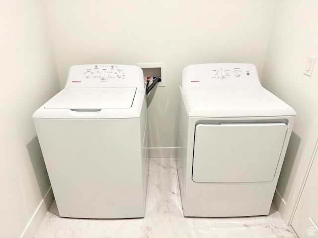 clothes washing area with marble finish floor, independent washer and dryer, baseboards, and laundry area