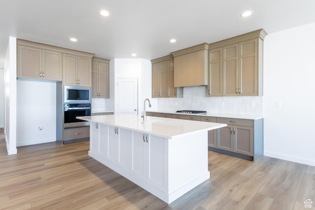 3047 N 2875 W Unit 7, Plain City, UT 84404 - kitchen featuring stainless steel appliances, backsplash, light countertops, light wood-style flooring, and a center island with sink