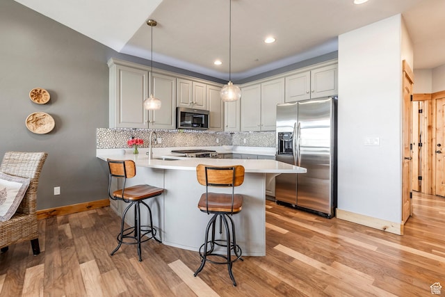 14084 N Council Fire Trl Unit 14D, Kamas, UT 84036 - kitchen featuring decorative backsplash, appliances with stainless steel finishes, a breakfast bar area, and light hardwood / wood-style flooring