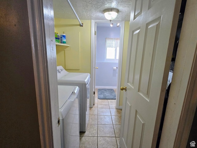 clothes washing area with light tile patterned flooring, a textured ceiling, and independent washer and dryer