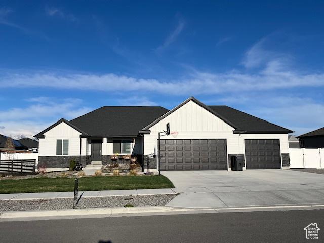 modern inspired farmhouse featuring board and batten siding, driveway, fence, and a garage
