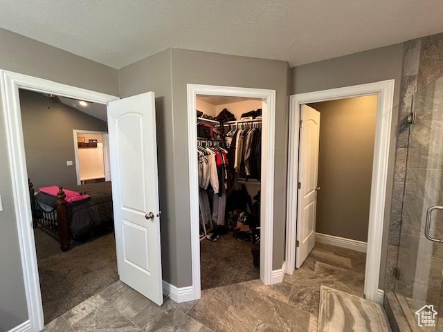 bathroom with a shower stall, baseboards, and a walk in closet