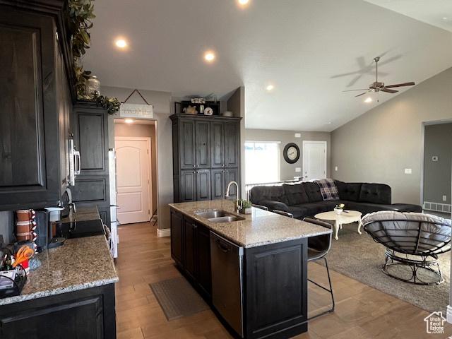 kitchen with vaulted ceiling, a kitchen island with sink, ceiling fan, dishwasher, and a sink