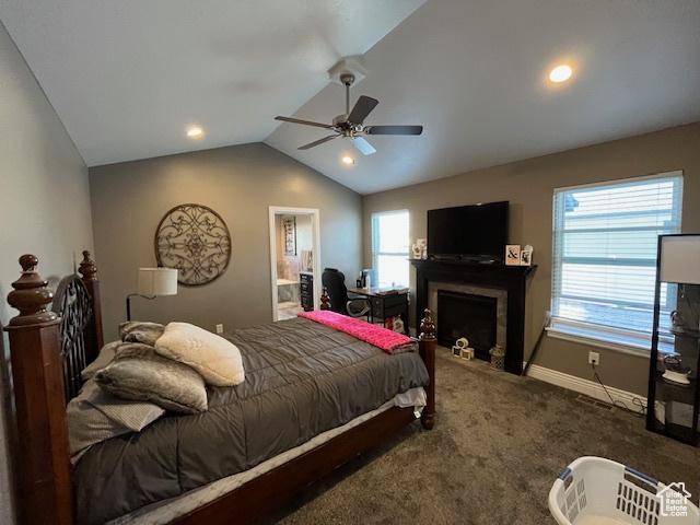 bedroom with baseboards, carpet, a fireplace, connected bathroom, and lofted ceiling