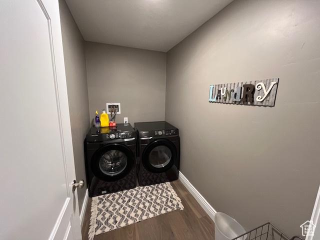 washroom featuring washer and dryer, laundry area, baseboards, and wood finished floors