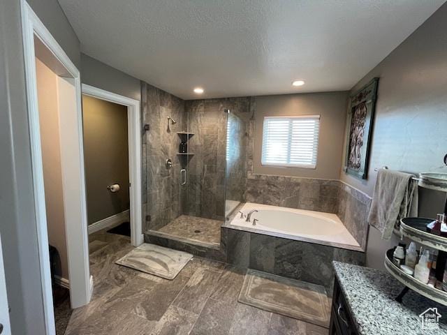 bathroom with a bath, a stall shower, and a textured ceiling