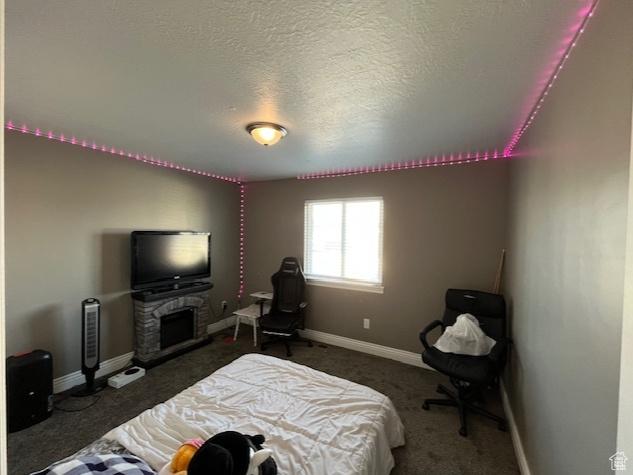 bedroom with baseboards, carpet, a fireplace, and a textured ceiling