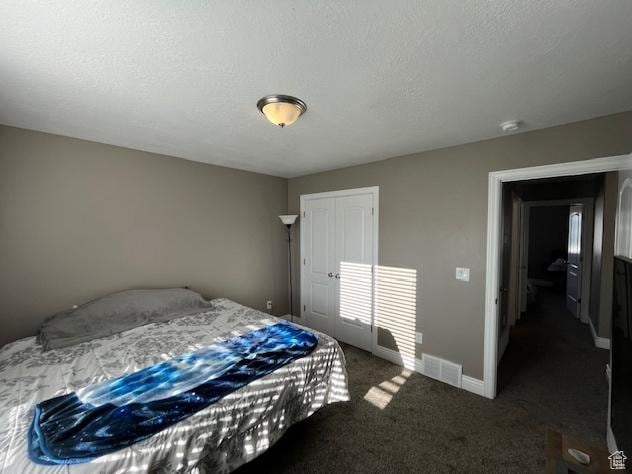 bedroom featuring a textured ceiling, a closet, visible vents, carpet floors, and baseboards