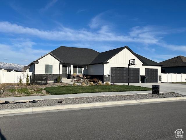 modern farmhouse with driveway, board and batten siding, a garage, and fence