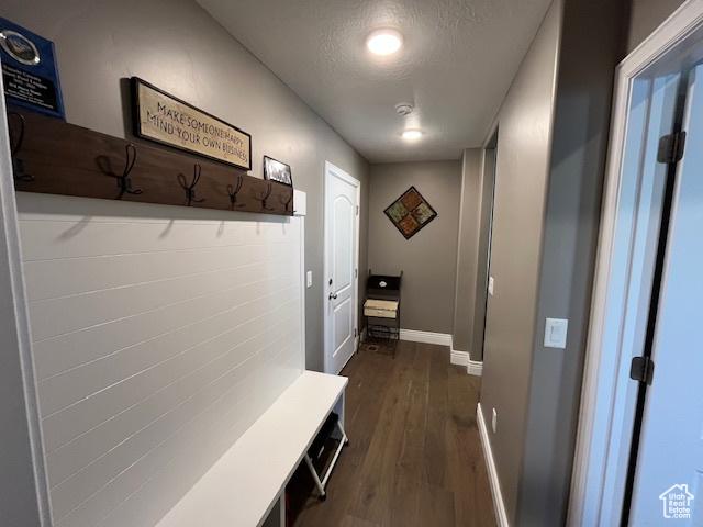 mudroom with dark wood-type flooring, a textured ceiling, and baseboards