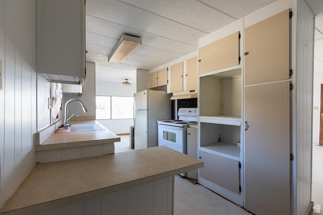 kitchen with cream cabinets, sink, wooden walls, and white appliances