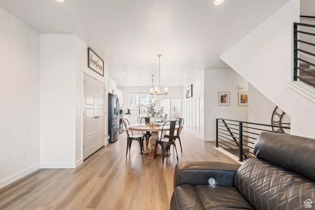 dining area with light hardwood / wood-style floors and a notable chandelier