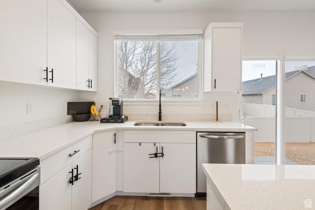 kitchen featuring sink, light stone counters, stainless steel dishwasher, dark hardwood / wood-style flooring, and white cabinets