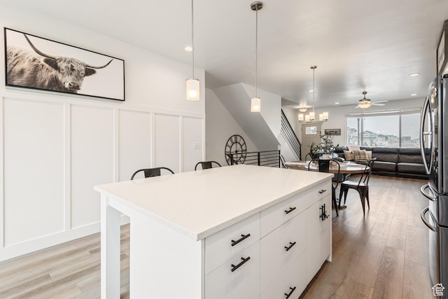 kitchen featuring white cabinetry, decorative light fixtures, light hardwood / wood-style floors, and a kitchen island