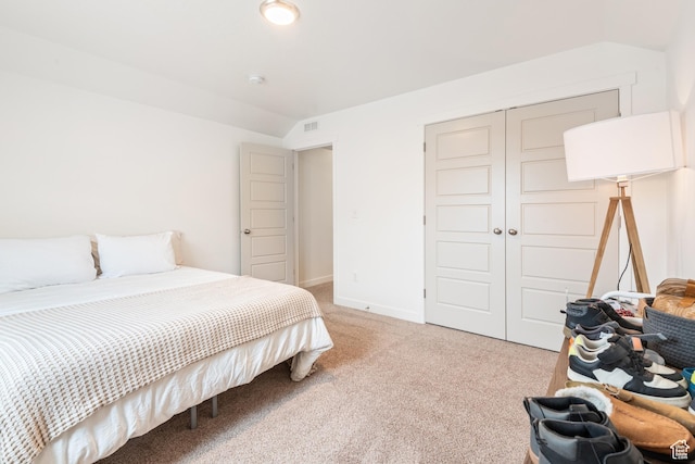 bedroom featuring lofted ceiling, light colored carpet, and a closet