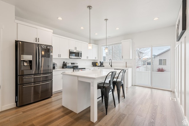 kitchen featuring a kitchen bar, a center island, white cabinets, and appliances with stainless steel finishes