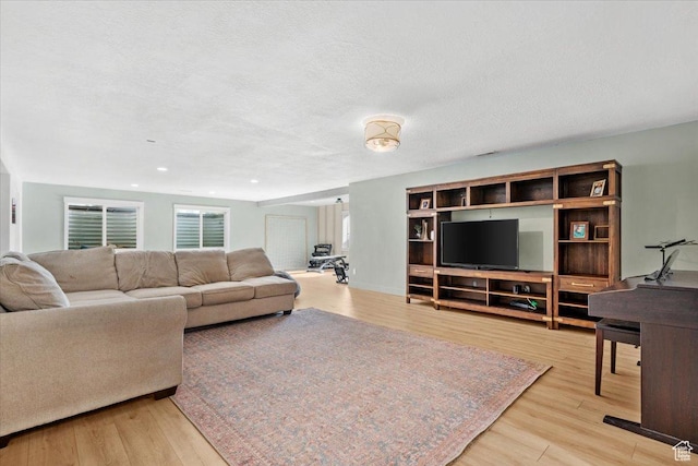 living room with a textured ceiling and light wood-type flooring