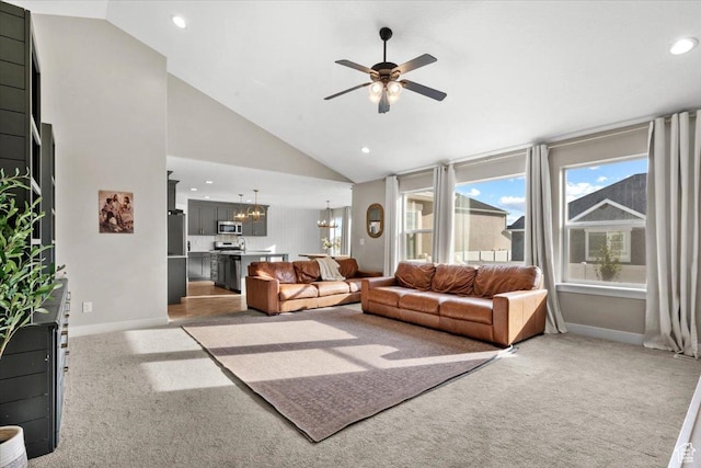 carpeted living room with ceiling fan with notable chandelier and high vaulted ceiling