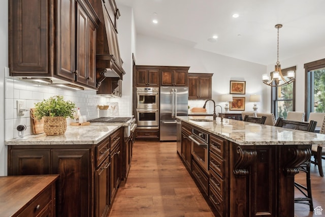 kitchen featuring sink, a kitchen bar, light stone counters, stainless steel appliances, and a spacious island