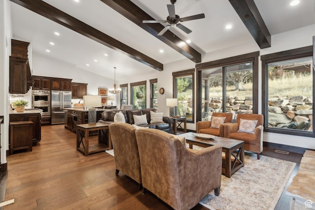 living room with vaulted ceiling with beams, hardwood / wood-style flooring, and ceiling fan with notable chandelier