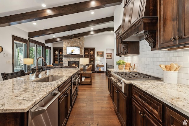 kitchen featuring sink, lofted ceiling with beams, light stone countertops, and appliances with stainless steel finishes
