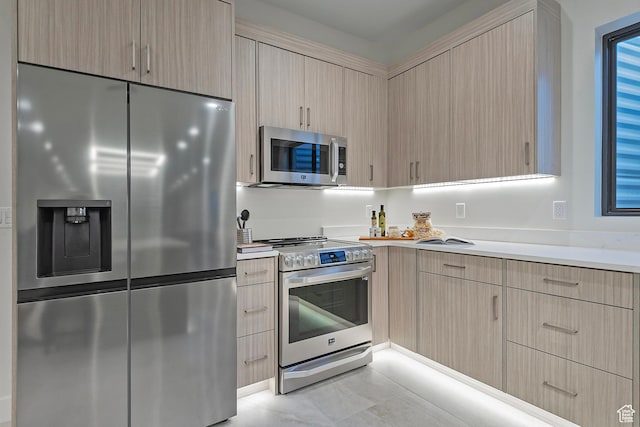 kitchen with light brown cabinets, appliances with stainless steel finishes, modern cabinets, and light countertops