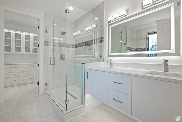 bathroom featuring double vanity, a stall shower, marble finish floor, and a sink