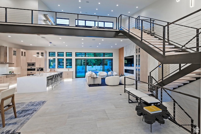 living area with stairway, recessed lighting, and a towering ceiling