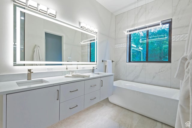 full bath with double vanity, a bathtub, marble finish floor, and a sink