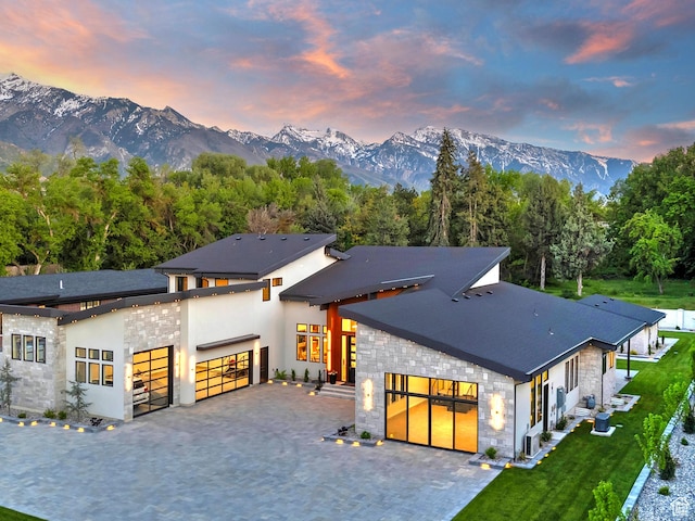 modern home with stone siding, a mountain view, and an attached garage
