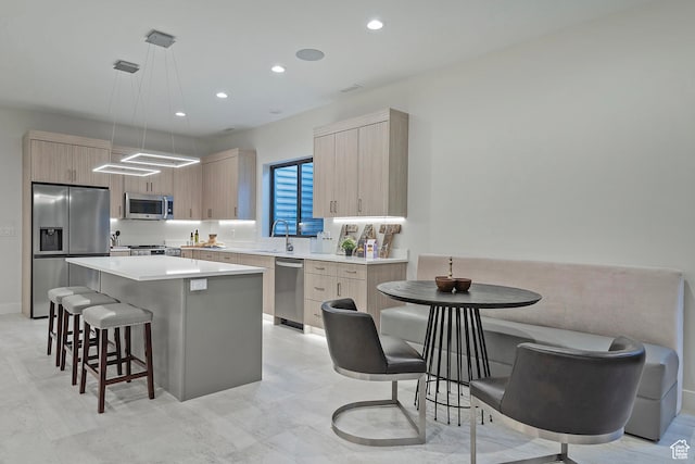 kitchen featuring a kitchen bar, modern cabinets, a kitchen island, stainless steel appliances, and light countertops