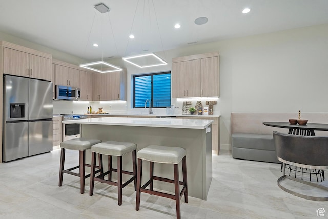 kitchen featuring a kitchen bar, a center island, light brown cabinetry, and stainless steel appliances