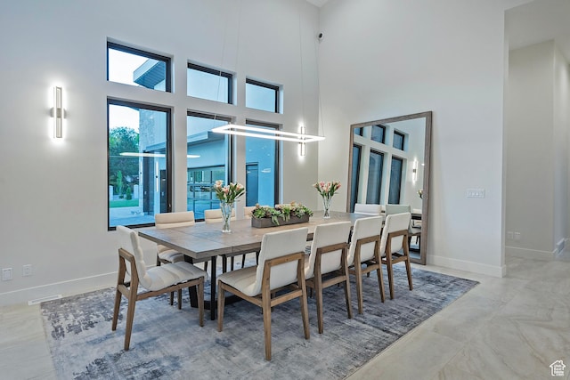 dining space with baseboards and a towering ceiling