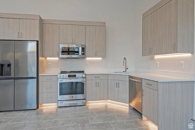 kitchen featuring light brown cabinets, light countertops, light tile patterned floors, stainless steel appliances, and a sink