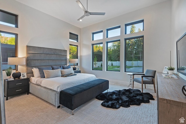 bedroom with light colored carpet, baseboards, a towering ceiling, and a ceiling fan