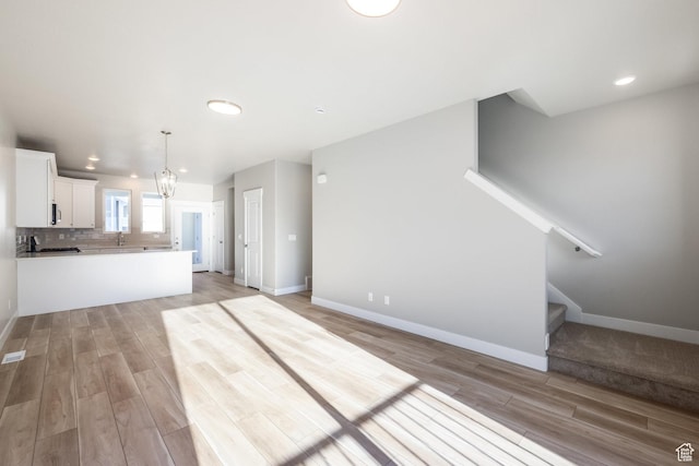 kitchen featuring decorative light fixtures, light hardwood / wood-style floors, decorative backsplash, and white cabinets
