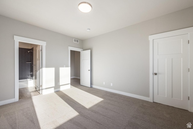 unfurnished bedroom with light colored carpet and connected bathroom