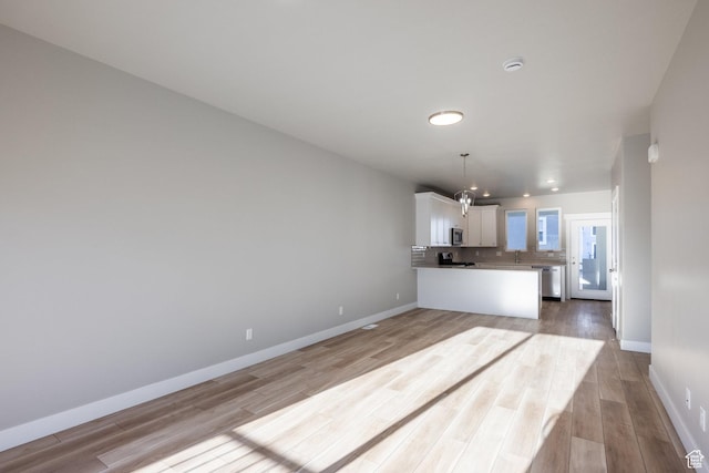 kitchen featuring white cabinetry, pendant lighting, light hardwood / wood-style floors, and decorative backsplash