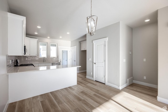 kitchen with light hardwood / wood-style flooring, stove, backsplash, white cabinets, and kitchen peninsula