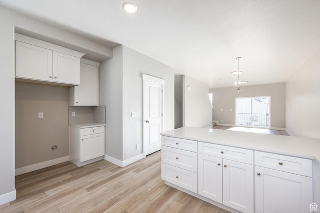 kitchen featuring tasteful backsplash, white cabinetry, pendant lighting, and light hardwood / wood-style flooring