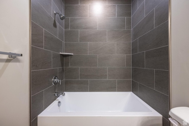 bathroom with toilet and tiled shower / bath