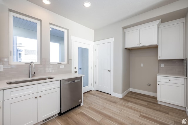kitchen featuring sink, dishwasher, white cabinetry, backsplash, and light wood-type flooring